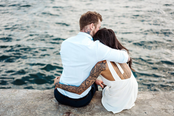 Junges Paar sitzt auf dem Pier am Meer - Foto, Bild