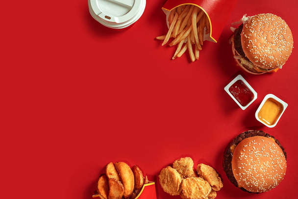 Fast food yemek üstten görünüm. Et burger, patates cipsi ve bardak içki kırmızı zemin üzerine. Paket servisi olan restoran kompozisyon. - Fotoğraf, Görsel