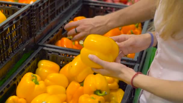 Young couple picking pepper in a supermarket - Felvétel, videó
