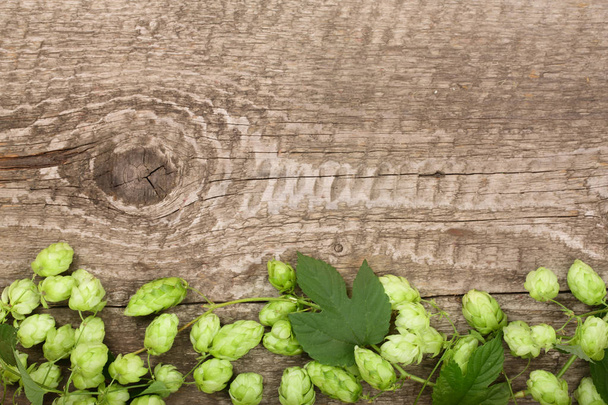 Зеленые хмелевые шишки на старом деревянном фоне. Ингредиент для производства пива. Вид сверху с пространством для копирования текста
 - Фото, изображение