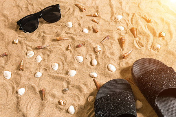 Σαγιονάρες μαύρο και sunglass, κοχυλιών στην άμμο. Με τη θέση για το κείμενό σας. Το Top view - Φωτογραφία, εικόνα