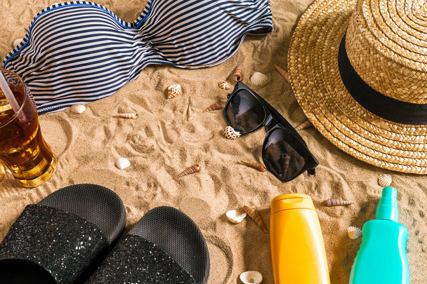 Bikini de verano y accesorios conjunto de playa con estilo, Bikini de playa traje de verano y arena de mar como fondo, Vista superior, Concepto
 - Foto, Imagen