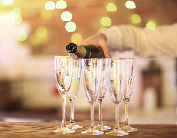 Copas de champán sobre mesa de madera con luces brillantes
 - Foto, Imagen
