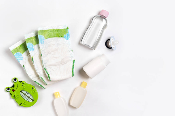 Babies goods diaper, baby powder, cream, shampoo, oil on white background with copy space. Top view or flat lay. - Foto, immagini