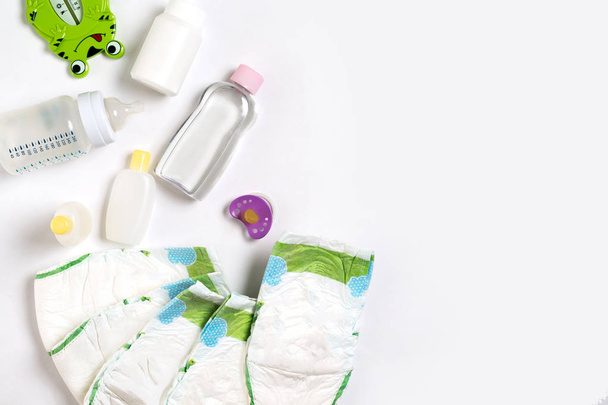 Babies goods diaper, baby powder, cream, shampoo, oil on white background with copy space. Top view or flat lay. - Foto, Bild
