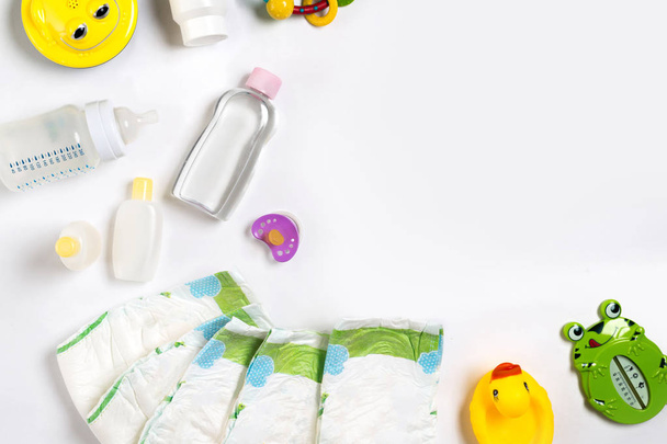 Baby's goederen luier, baby-poeder, crème, shampoo, olie op witte achtergrond met kopie ruimte. Bovenaanzicht of plat lag. - Foto, afbeelding