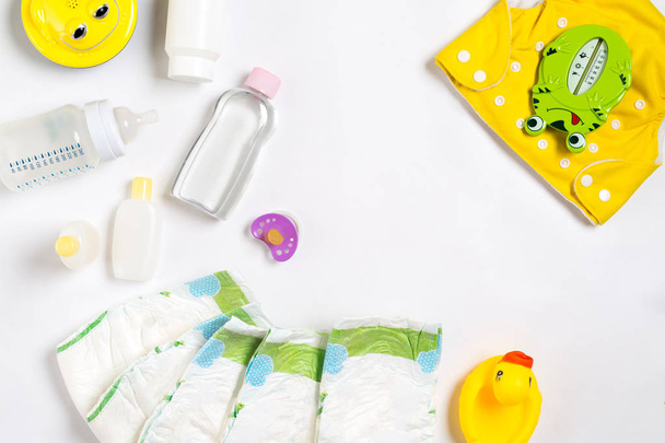 Babies goods diaper, baby powder, cream, shampoo, oil on white background with copy space. Top view or flat lay. - Fotó, kép