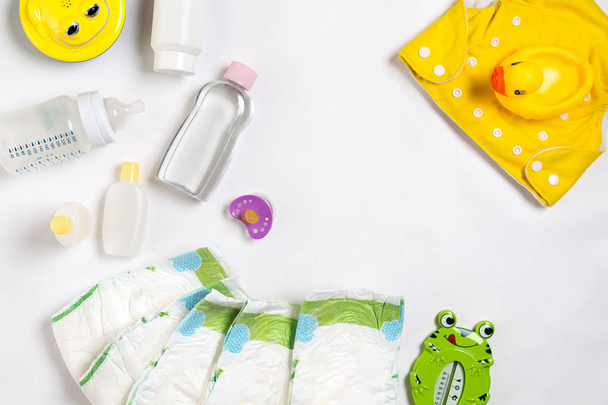 Baby's goederen luier, baby-poeder, crème, shampoo, olie op witte achtergrond met kopie ruimte. Bovenaanzicht of plat lag. - Foto, afbeelding