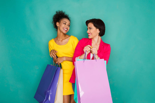 Emocionadas chicas multiétnicas con bolsas de compras
 - Foto, imagen