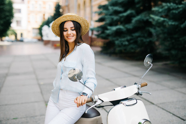 Beleza na scooter. Jovem excitada e bela mulher sentada perto de scooter na rua
 - Foto, Imagem