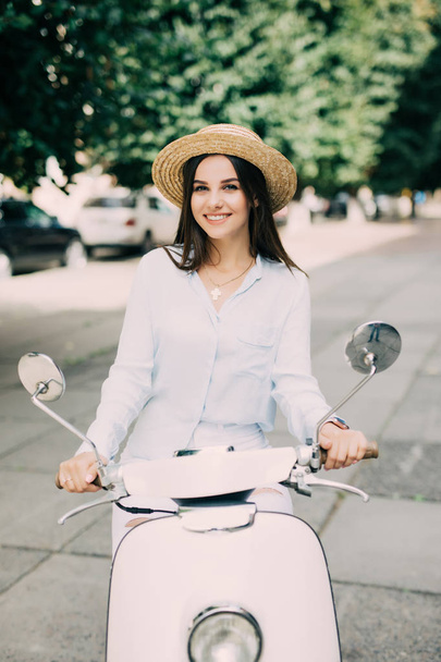 menina bonita em um chapéu em uma camiseta branca e chapéu posando em uma scooter
 - Foto, Imagem