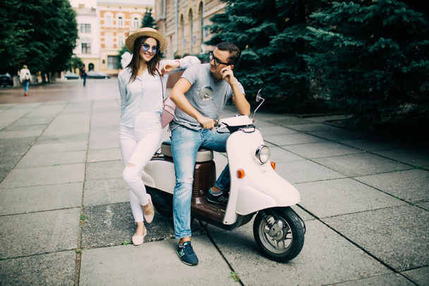 Belo jovem casal sentado em scooter juntos na rua da cidade
 - Foto, Imagem