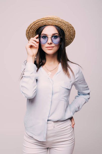 Молодая девушка позирует в шляпе и очках в белой стене
 - Фото, изображение