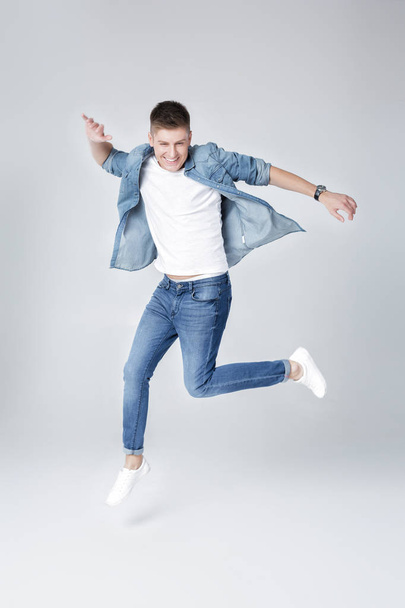 handsome man in jeans and jacket jumping - Photo, Image