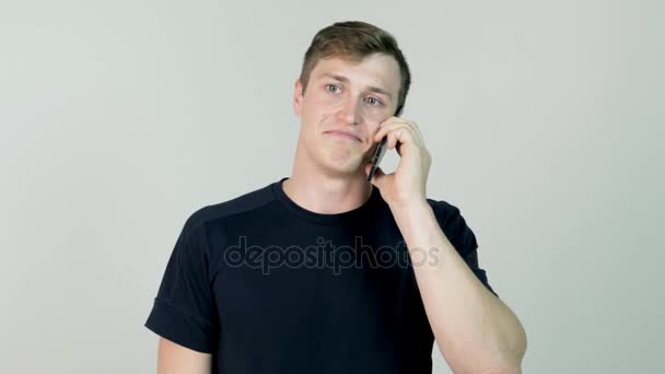 Portrait of a casual young man speaking on the phone. Young man is standing with mobile phone and is talking with his girlfriend - Imágenes, Vídeo