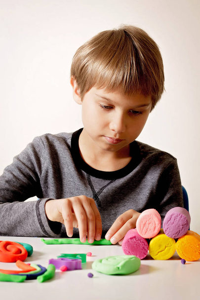 Хлопчик грає і створює з моделювання глини або пластиліну
. - Фото, зображення