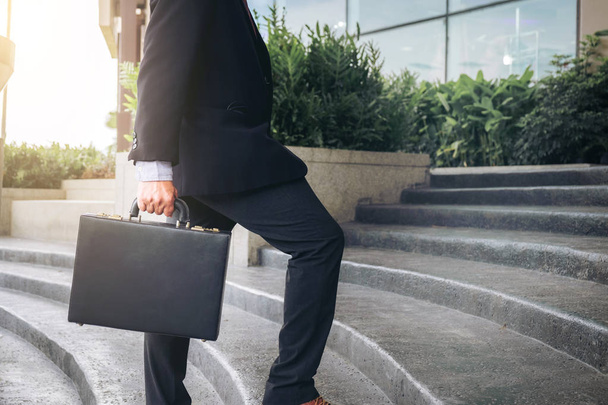 Businessman walking up the stairs and holding a briefcase in han - Foto, immagini