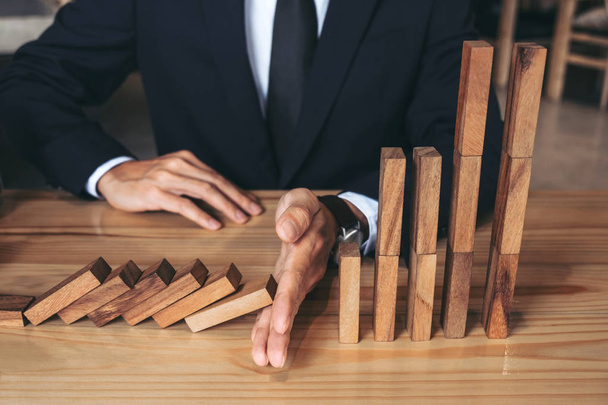 Close up of businessman hand Stopping Falling wooden Dominoes ef - 写真・画像