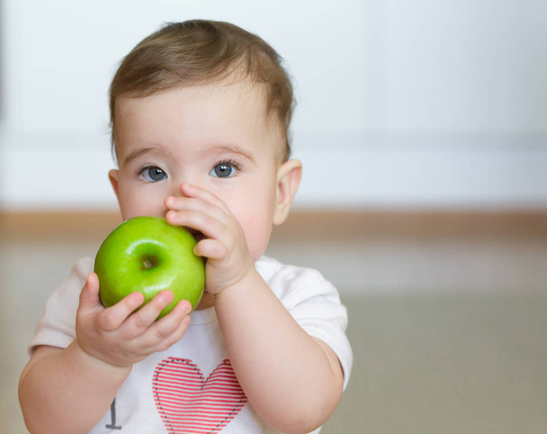 Little child with a green apple in his hands. Close up portrait - Φωτογραφία, εικόνα