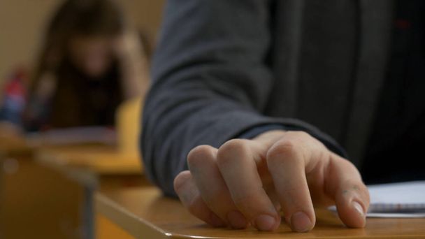 Φοιτητής χέρι δάχτυλο υποκλοπή closeup. Νεαρός άνδρας βρύσες τα δάχτυλά του σε έναν πίνακα - Φωτογραφία, εικόνα