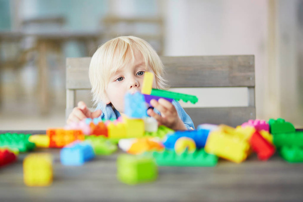 Little boy playing with colorful plastic construction blocks - Valokuva, kuva