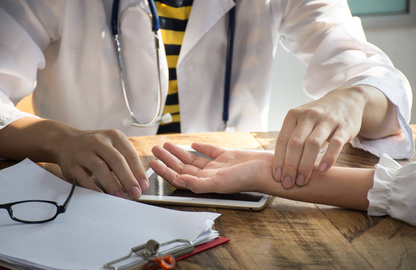 Primer plano médico asiático está comprobando el pulso de la paciencia por los dedos
 - Foto, imagen