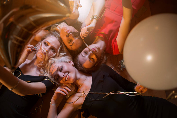 Visão de baixo ângulo de quatro belas mulheres caucasianas brincando fazendo bigode falso de seu próprio cabelo deitado na mesa no café
, - Foto, Imagem