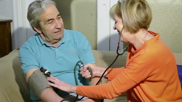 Νοσοκόμα, ελέγχει την πίεση του αίματος από έναν ηλικιωμένο άνδρα εβδομήντα ετών στο σπίτι. - Πλάνα, βίντεο