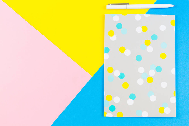 Top view of paper notebook with pen on blue, yellow and pink background. - Photo, Image
