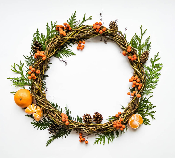Festive wreath of vines with tangerines, thuja branches, rowanberries and cones. Flat lay, top view - Fotoğraf, Görsel