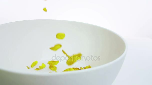 cereal corn flakes falling down in a bowl, shot in slow motion on white background, concept of diet healthy food  - Filmati, video