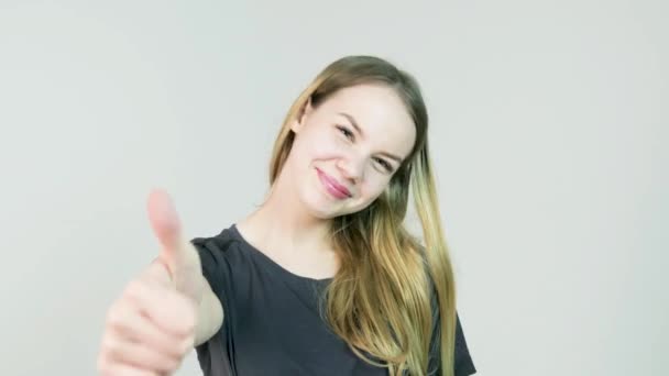 Щаслива усміхнена красива молода жінка показує великі пальці вгору жестом на білому тлі
 - Кадри, відео