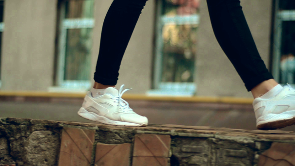 close up of girl in sneakers walks in the street - Materiał filmowy, wideo