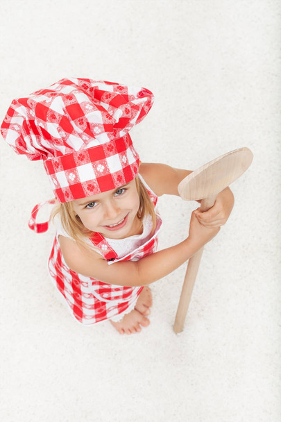 Little chef with apron and hat holding a large wooden spoon - lo - Foto, afbeelding