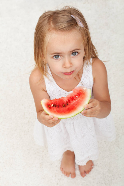 Νεαρό κορίτσι τρώει μια φέτα καρπούζι - κάτοψη - Φωτογραφία, εικόνα