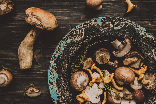 Fresh mixed forest mushrooms on the wooden black table - Photo, Image