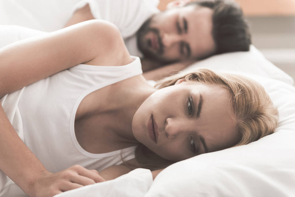 Anxious girl cannot sleep near her husband in bedroom - 写真・画像