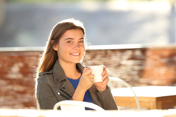 Girl drinking coffee and looking at camera in a bar - Φωτογραφία, εικόνα