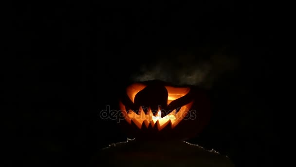Gesneden Halloween pompoen lampjes binnen met vlam op een zwarte achtergrond close-up - Video