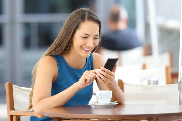 Happy woman using a smart phone in a bar terrace - Photo, Image