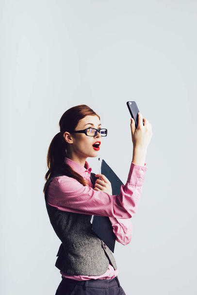 Surprised businesswoman girl looks into the phone, wearing a suit. Shock news - Valokuva, kuva