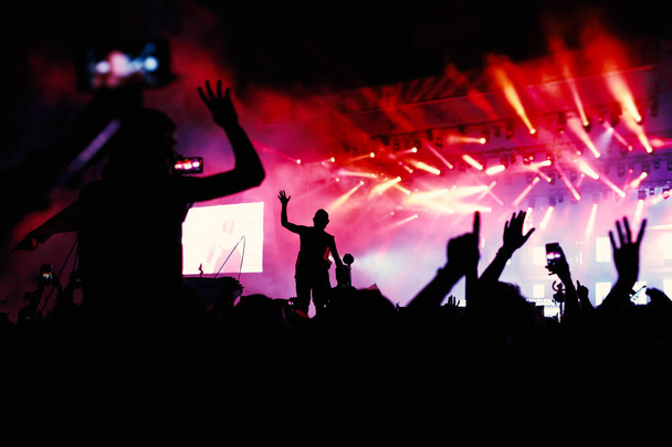 siluetas de manos en concierto frente a luces brillantes de la etapa - Foto, imagen