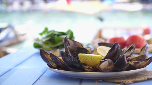 Plato de mariscos mejillones abiertos y listos en la mesa azul en el restaurante con vista al mar de la costa en Foca Izmir Turquía
. - Metraje, vídeo