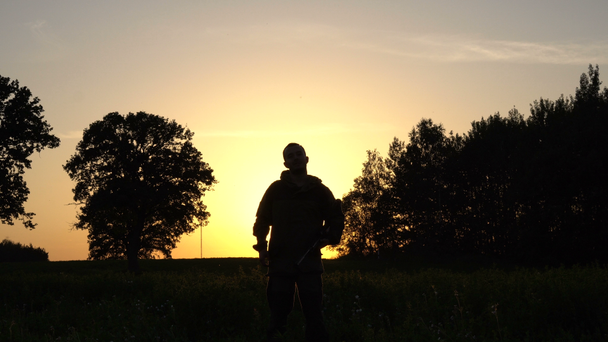 mies, jolla on ase kättelee taustaa vasten auringonnousun 4 k
 - Materiaali, video