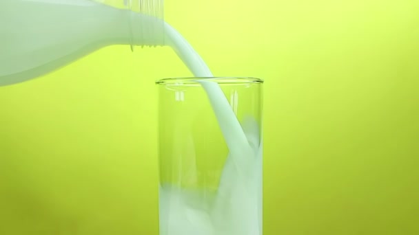 fresh white milk pouring into drinking glass on yellow gold background, shooting with slow motion, diet and healthy nutrition  - Materiał filmowy, wideo