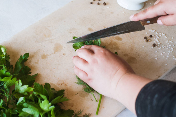 Cook woman cutting green parsley on desk - Фото, зображення
