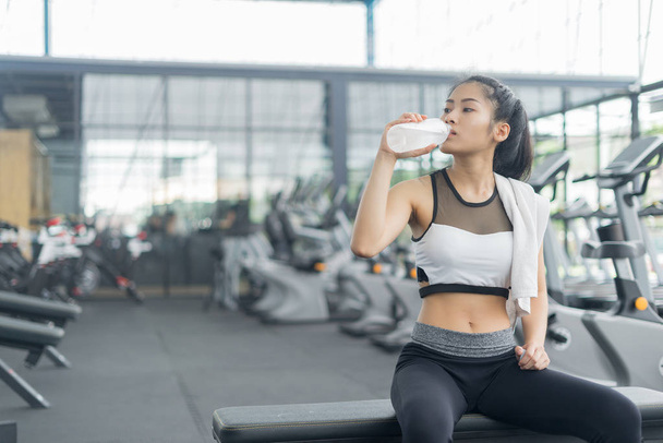 Фитнес-женщина в тренировке питьевой воды после занятий в тренажерном зале, спортивная концепция - Фото, изображение