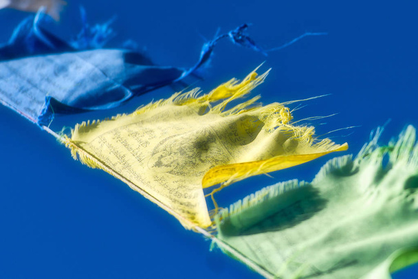 Μπλε, κίτρινο και πράσινο θιβετιανή βουδιστική προσευχή σημαίες ανεμίζουν στο t - Φωτογραφία, εικόνα