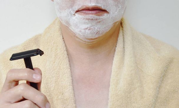  гоління крем на обличчі людини з чорною бритвою на правій руці приготуватися до гоління
 - Фото, зображення