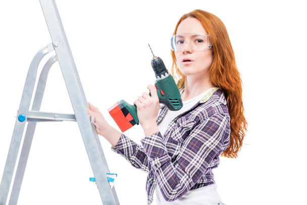girl with a drill on a stepladder posing on a white background - Photo, Image